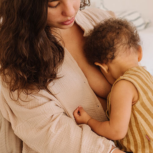 Una madre amamanta a su hijo mientras está sentada en la cama - solucionesbanohub.compaña - 1