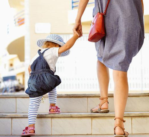 Una niñera y una niña suben unas escaleras mientras se dan la mano - solucionesbanohub.compaña - 1