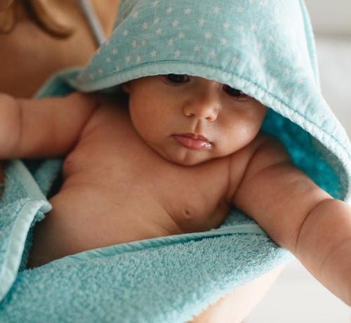 Un bebé con albornoz recién bañado y limpiado con jabones Mustela - solucionesbanohub.compaña - 1