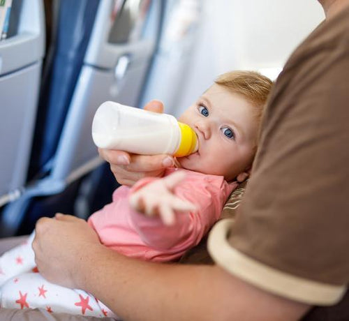 Un padre le da el biberón a su hija mientras viajan en avión - solucionesbanohub.compaña - 1