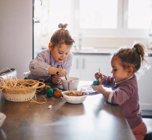 Dos hermanas pintan huevos de pascua en la cocina de su casa - solucionesbanohub.compaña - 1