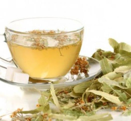 Una taza con infusión de tila, un par de azucarillos y rodeada de hojas de tilo - solucionesbanohub.compaña - 1