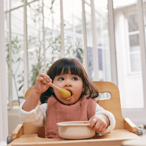Bebé niña sobre su silla comedor comiendo un pure con una cuchara - solucionesbanohub.compaña - 1
