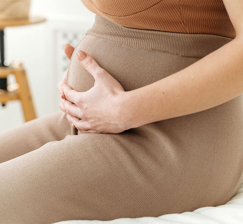 Mujer embarazada sentada abrazando su tripa - solucionesbanohub.compaña - 1