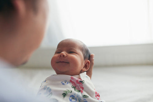 Bebé de unos 0 a 3 meses cogido entre los brazos de su padre sonriendo. - solucionesbanohub.compaña - 1