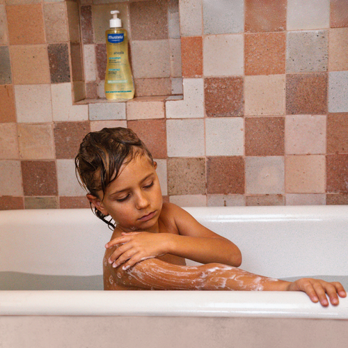 Niño en una bañera usando el aceite de ducha de Mustela. - solucionesbanohub.compaña - 1