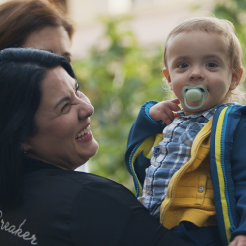 Mamá sonriendo mientras coge en brazos a su hijo - solucionesbanohub.compaña - 1