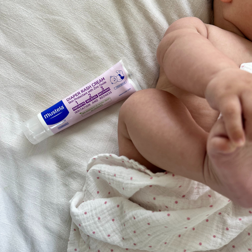 Hora del cambio del pañal del bebé con el bebé recostado y la crema bálsamo 1 2 3 de Mustela. - solucionesbanohub.compaña - 1