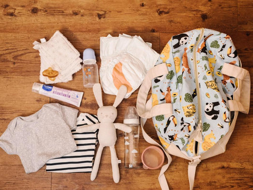 Una familia prepara la maleta de viaje de su bebé colocando todo lo necesario encima de la mesa - solucionesbanohub.compaña - 1