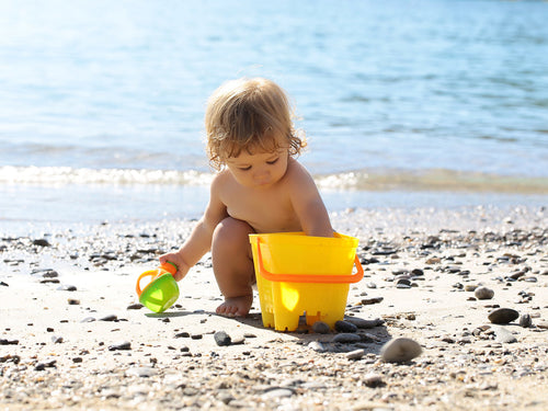 Un niño juega en la playa protegido por la crema solar Mustela adecuada, porque su madre conoce el fototipo de la piel de su bebé - solucionesbanohub.compaña - 1