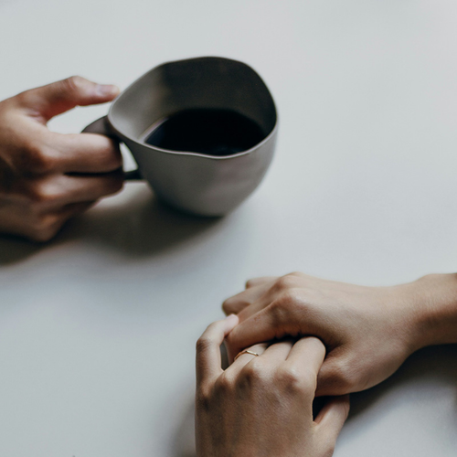 Mujer agarrándose las manos y un café - solucionesbanohub.compaña - 1