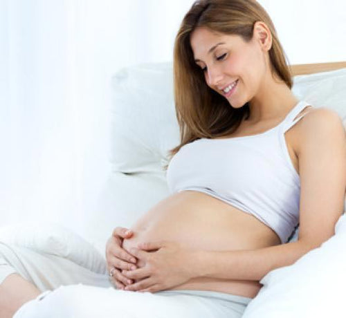 Mujer sentada en un sillon blanco tocándose la tripa - solucionesbanohub.compaña - 1