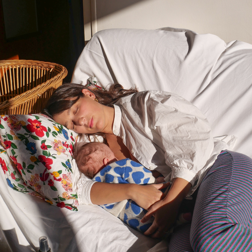 Una mamá dormida en un sillón mientras abraza a su bebé.. - solucionesbanohub.compaña - 1