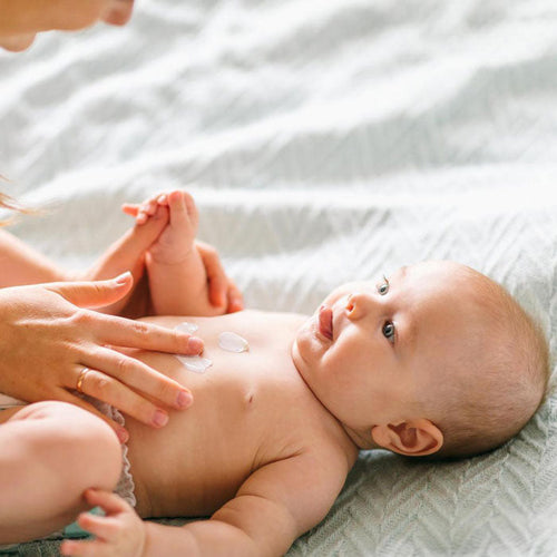 Mamá masajeando a su bebé con crema. - solucionesbanohub.compaña - 1