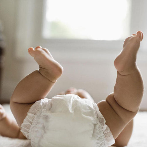 Bebé con los pies en alto preparado para darle un masaje. - solucionesbanohub.compaña - 1