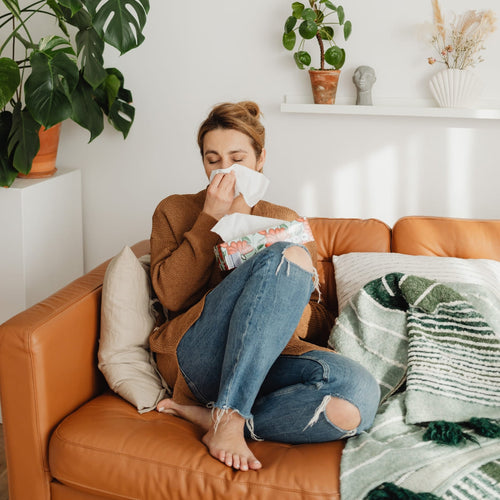 mujer sonándose la nariz sentada en su sofa - solucionesbanohub.compaña - 1