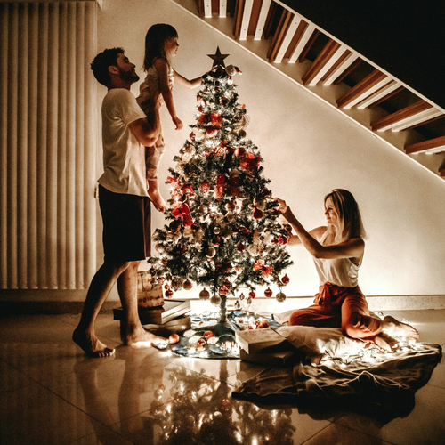 Padres con su hija pequeña decorando el árbol de navidad - solucionesbanohub.compaña - 1