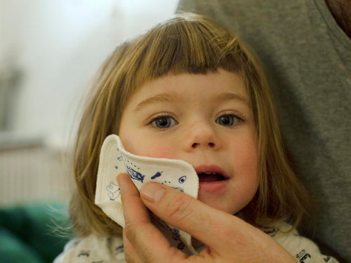 Una madre está limpiando la cara de su niña con una toallita reutilizable - solucionesbanohub.compaña - 1