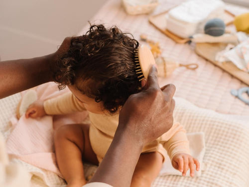 Un padre está peinando el cabello rizado de su niña después de aplicar el agua para peinar de Mustela - solucionesbanohub.compaña - 6