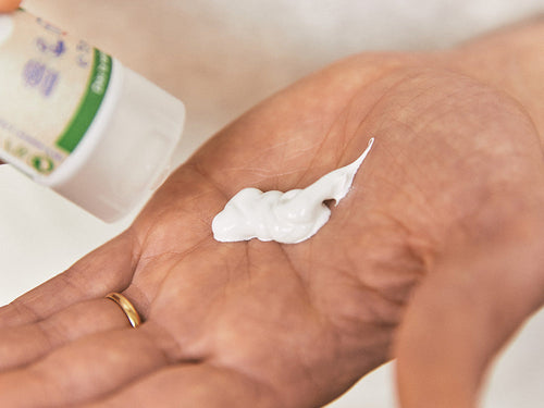 Padre aplica en la palma de la mano un poco de crema para la dermatitis del pañal, o también llamada pañalitis. - solucionesbanohub.compaña - 4