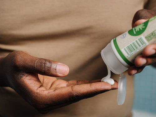 Padre aplicándose crema hidratante bio Mustela en la mano, ideal para toda la familia. - solucionesbanohub.compaña - 4