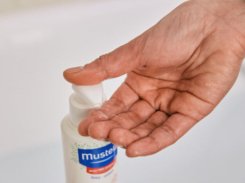Madre se pone un poco de gel de baño confort en la mano lavar la piel sensible de su bebé. - solucionesbanohub.compaña - 5