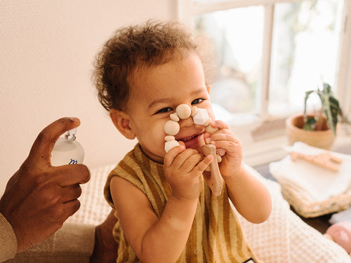 Padre aplica colonia perfumada para bebés de Mustela en su hijo. rollover - solucionesbanohub.compaña - 3
