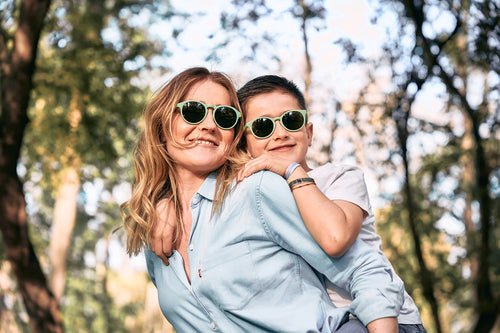 Una madre juega con su hijo en la montaña y llevan gafas de sol ecológicas de Mustela en color verde para proteger sus ojos. - solucionesbanohub.compaña - 8
